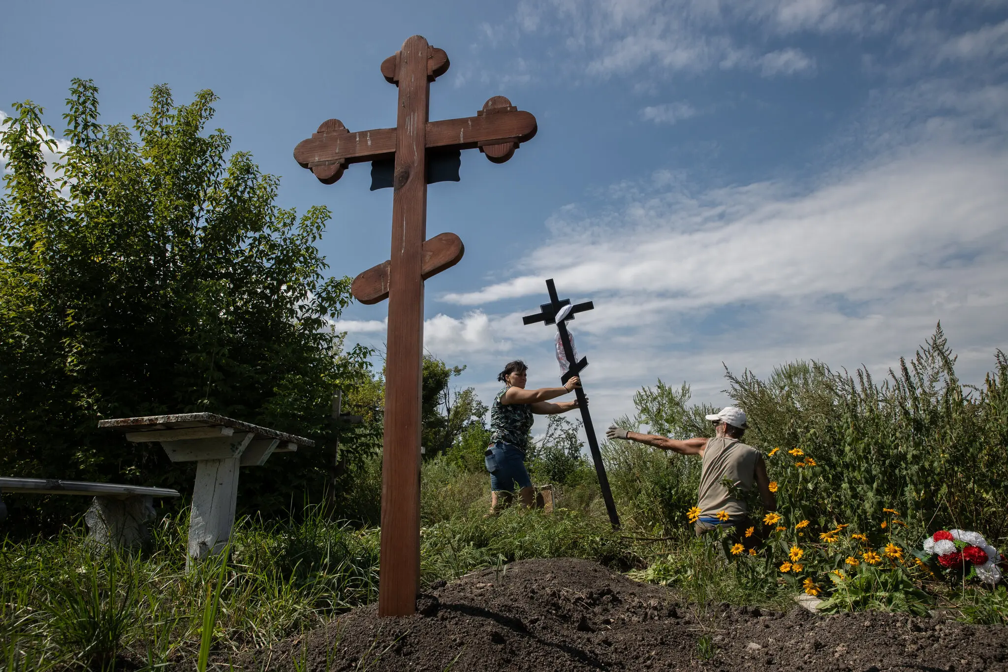 Жителі села встановлюють хрест на цвинтарі, де поховані їхні рідні.